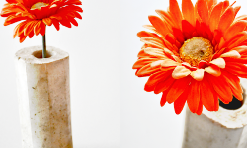 Betonvase mit oranger Blume