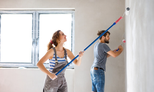Junges Paar streicht ihre Wohnzimmerwand